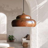 handmade copper pendant light hanging in a room with a neutral color palette