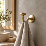 Classic solid brass double wall hook with linen towel beside an oak vanity