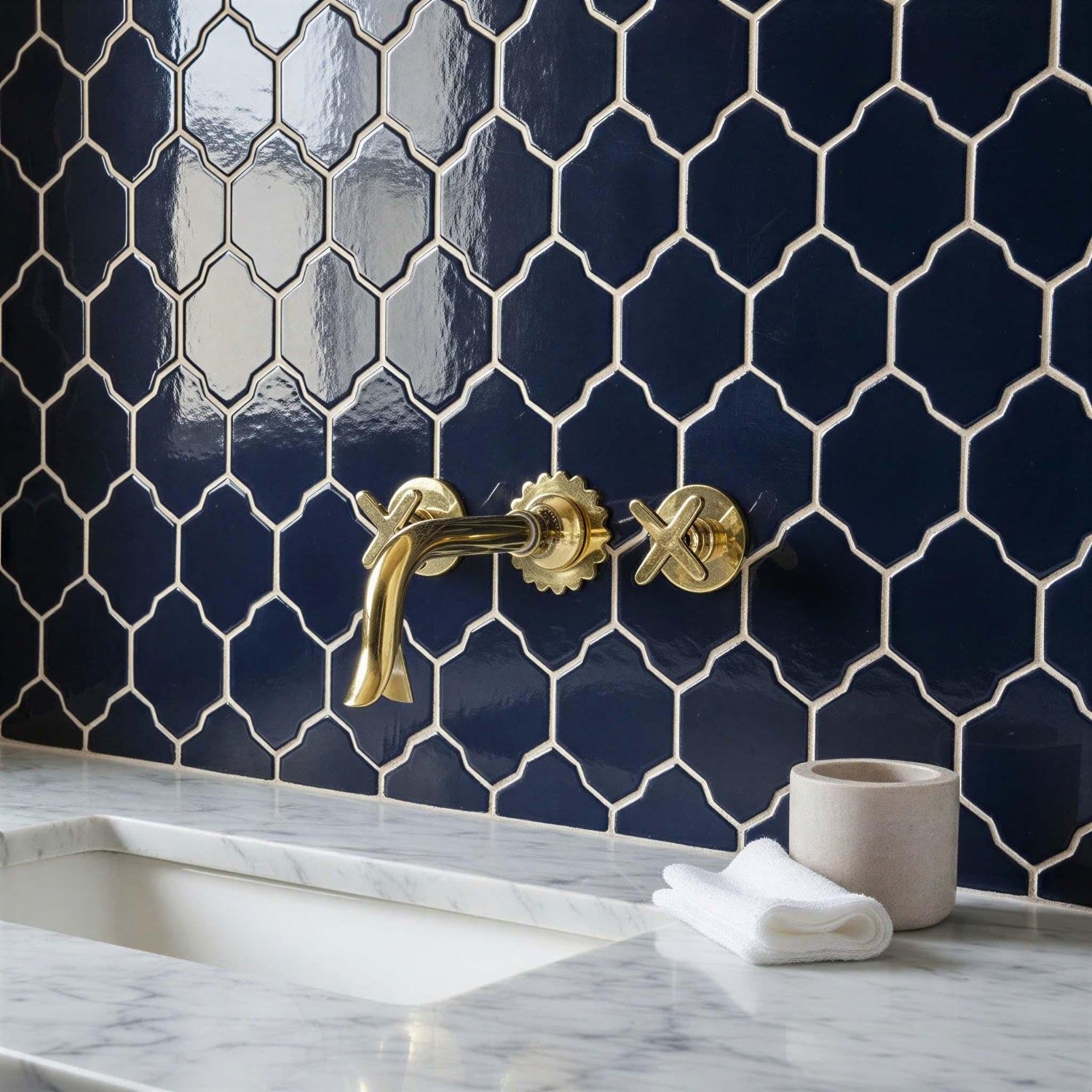 Bathroom with navy hexagonal tiles, gold faucet, and marble countertop.