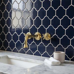 Bathroom with navy hexagonal tiles, gold faucet, and marble countertop.