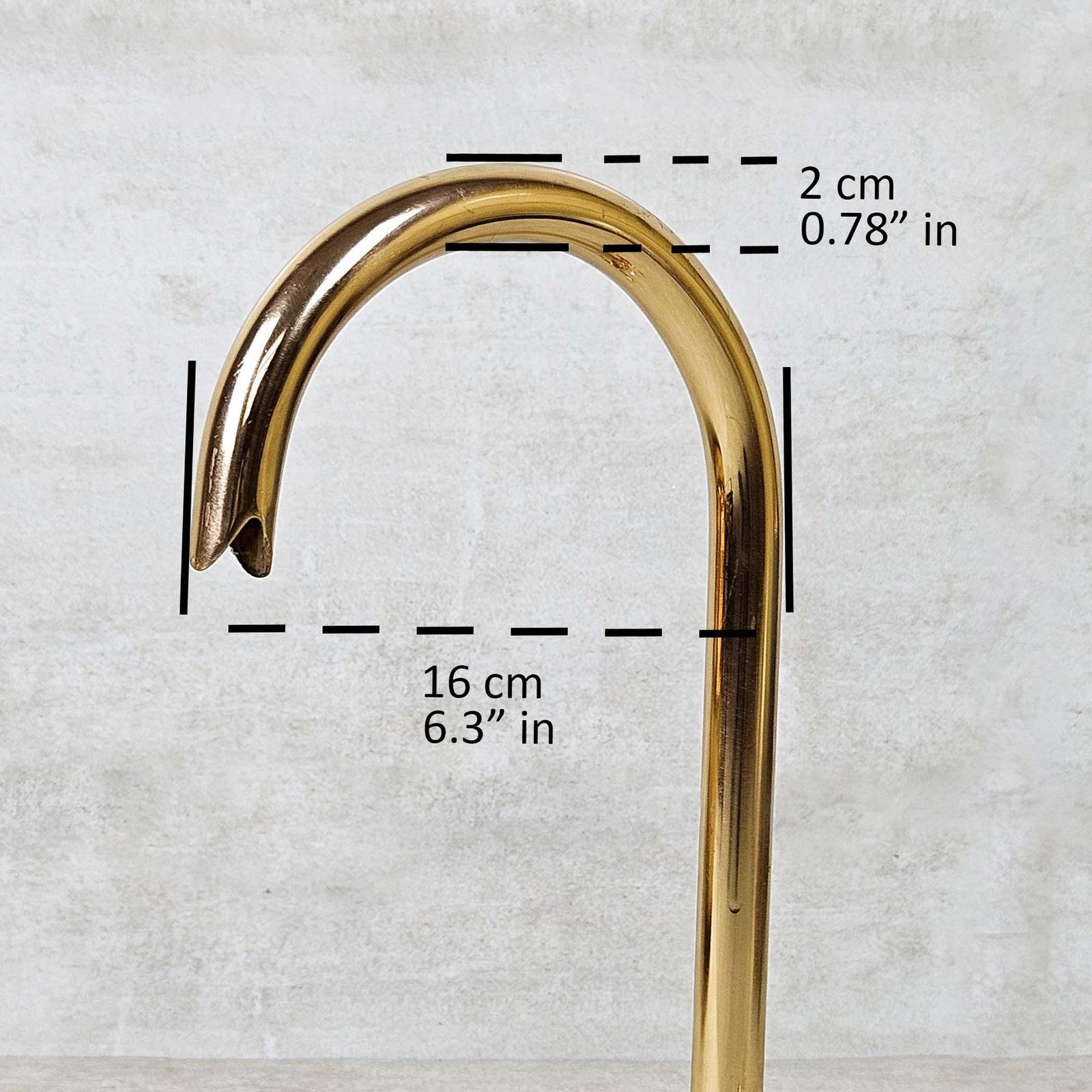 Gold-colored curved object with measurements on a light gray background