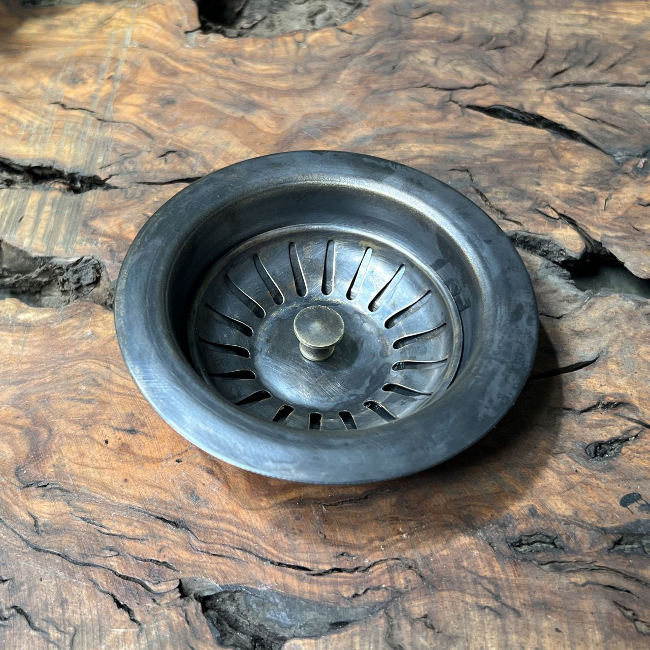 Metal sink drain basket on a wooden surface