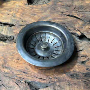 Metal sink drain basket on a wooden surface