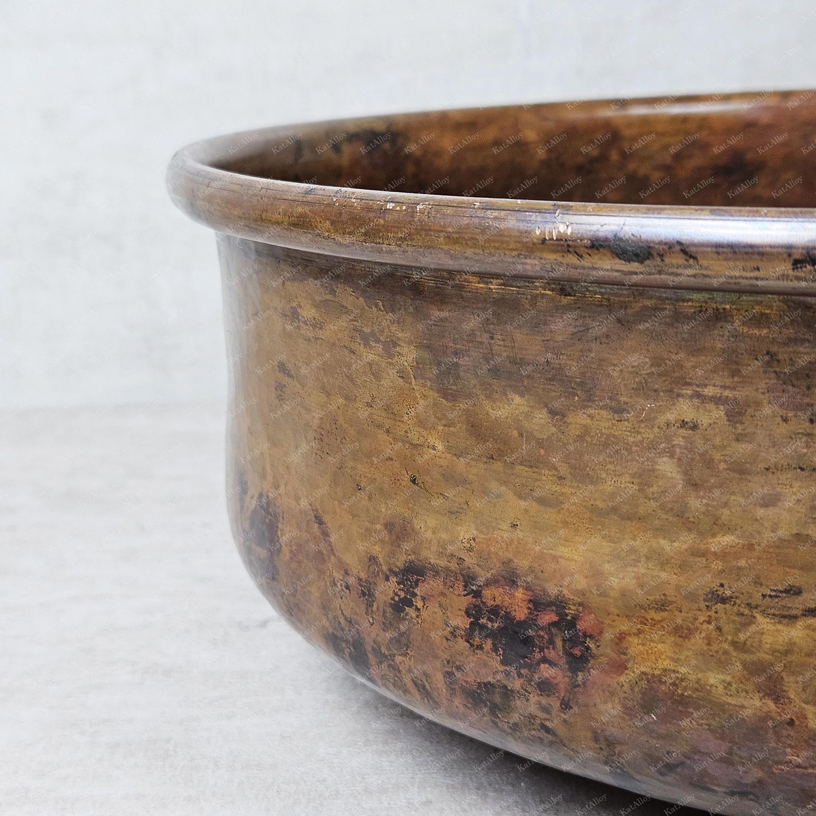 Close-up of a copper pot with a textured surface on a light gray background