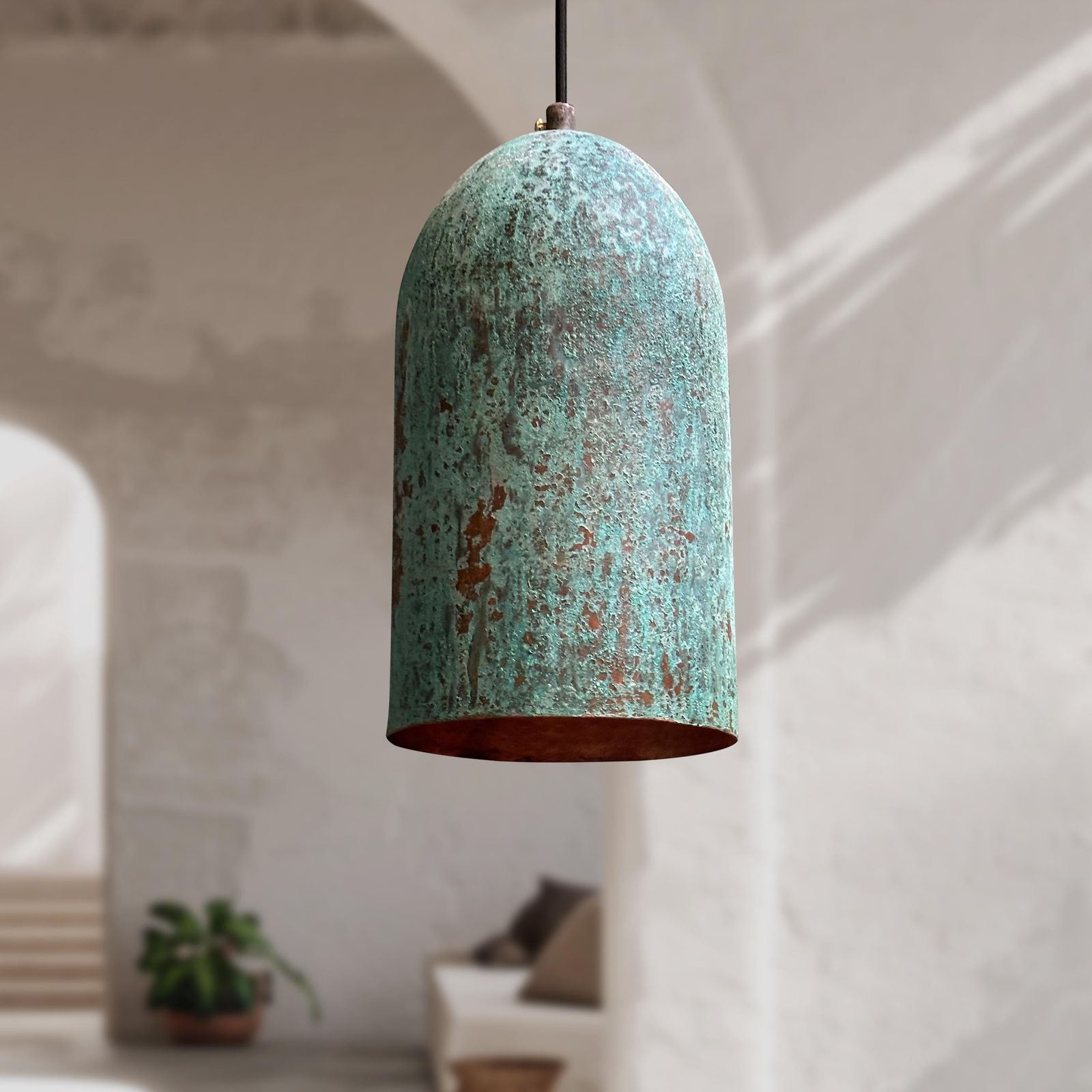 Rustic pendant light with a textured green and brown finish hanging in a room.