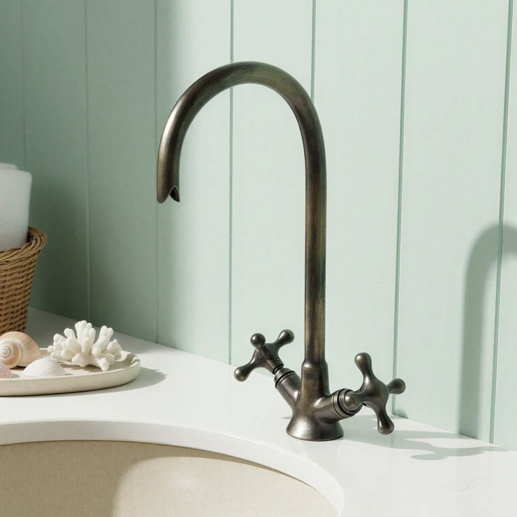 Bronze faucet on a white sink with a light green wall in the background