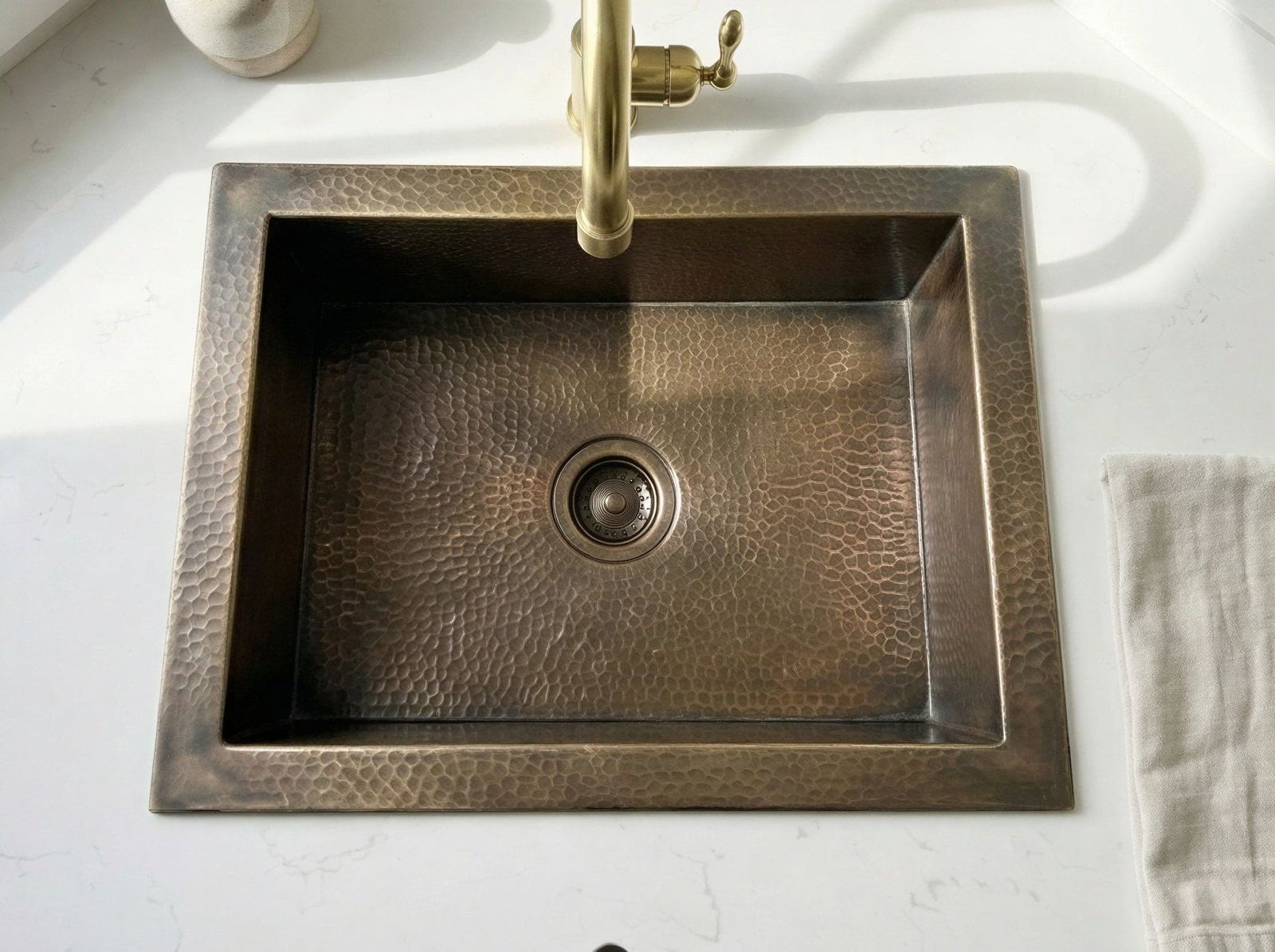 bronze brass sink with gold faucet on a white countertop