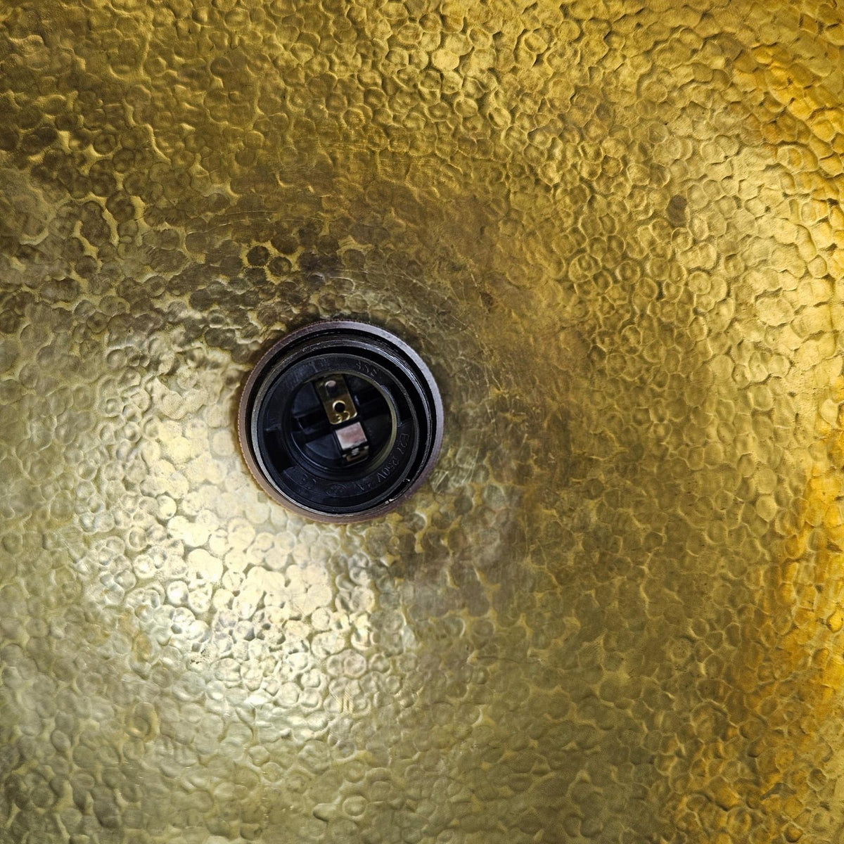 Close-up of a textured gold surface with a central drain hole.