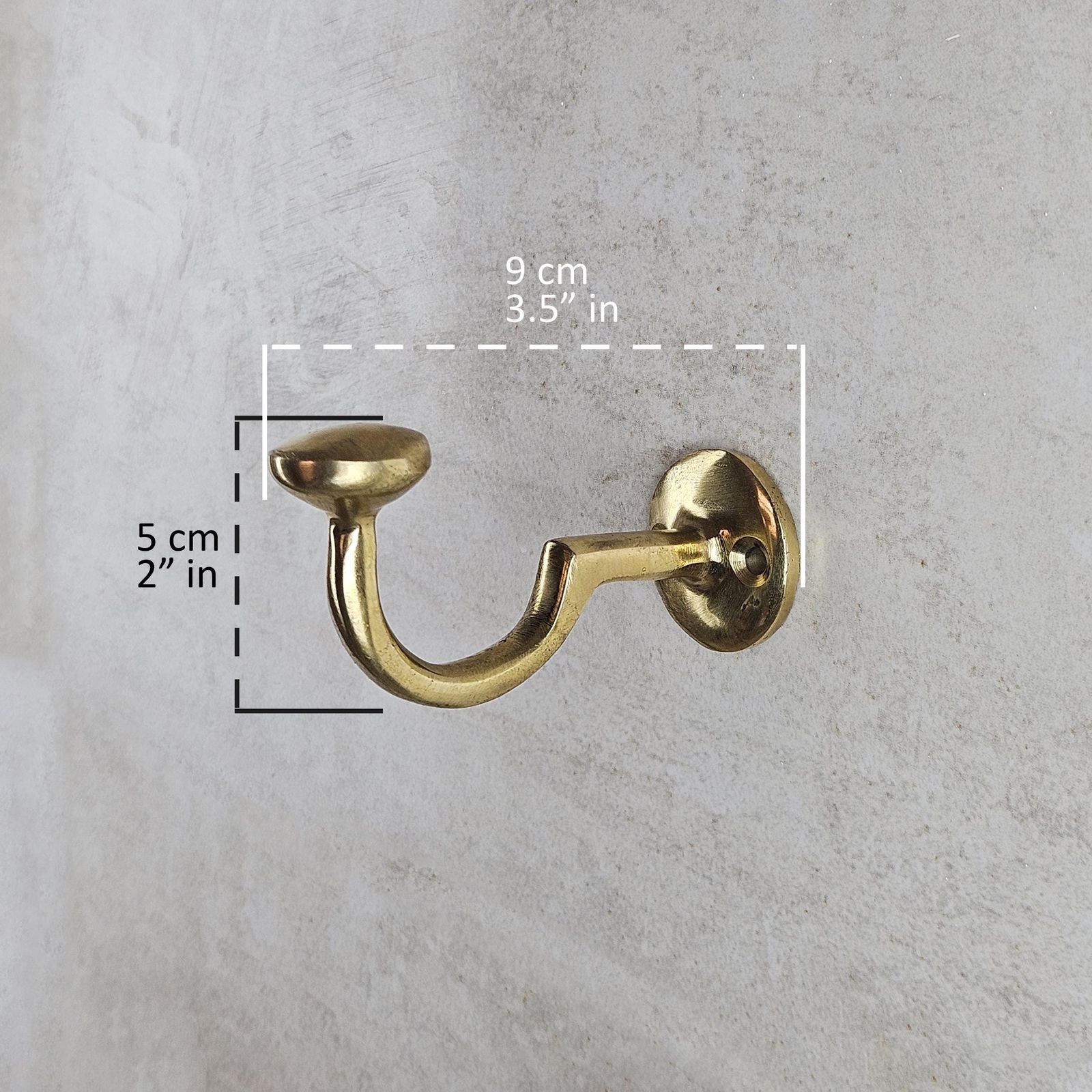 Gold wall hook with measurements on a gray concrete background
