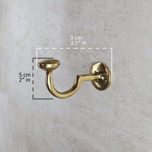 Gold wall hook with measurements on a gray concrete background