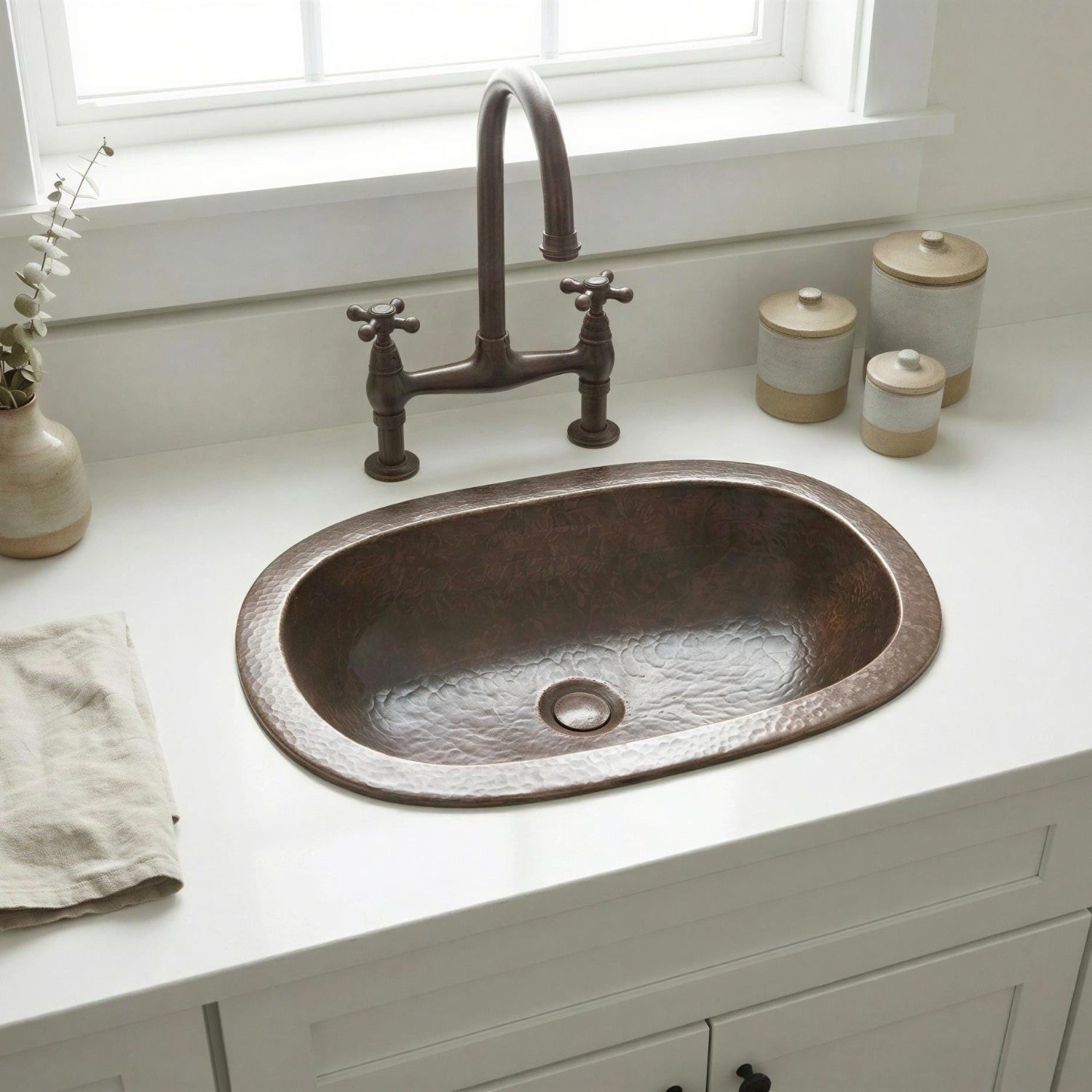 Copper sink on a white countertop with a window in the background