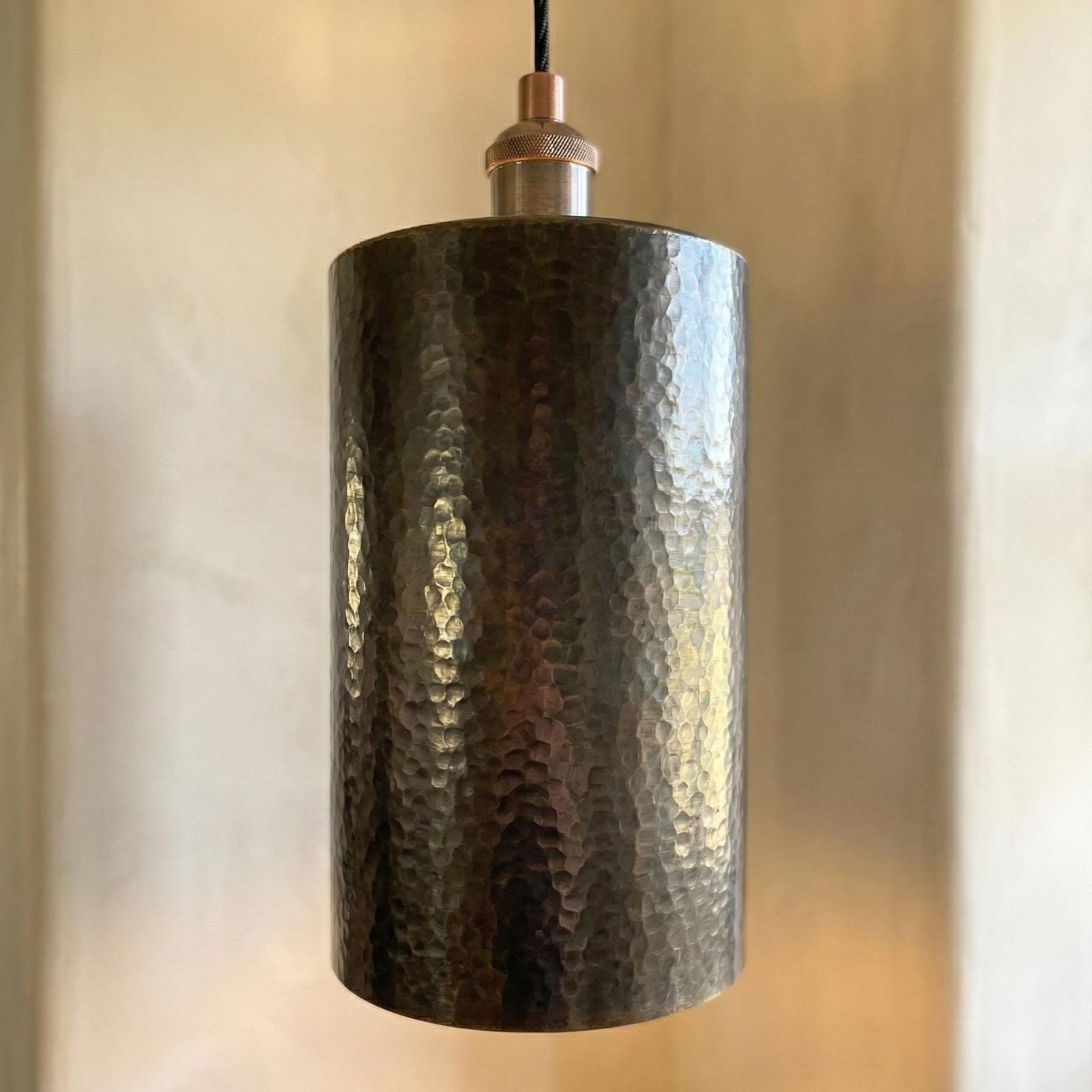 Hammered metal pendant light against a neutral background