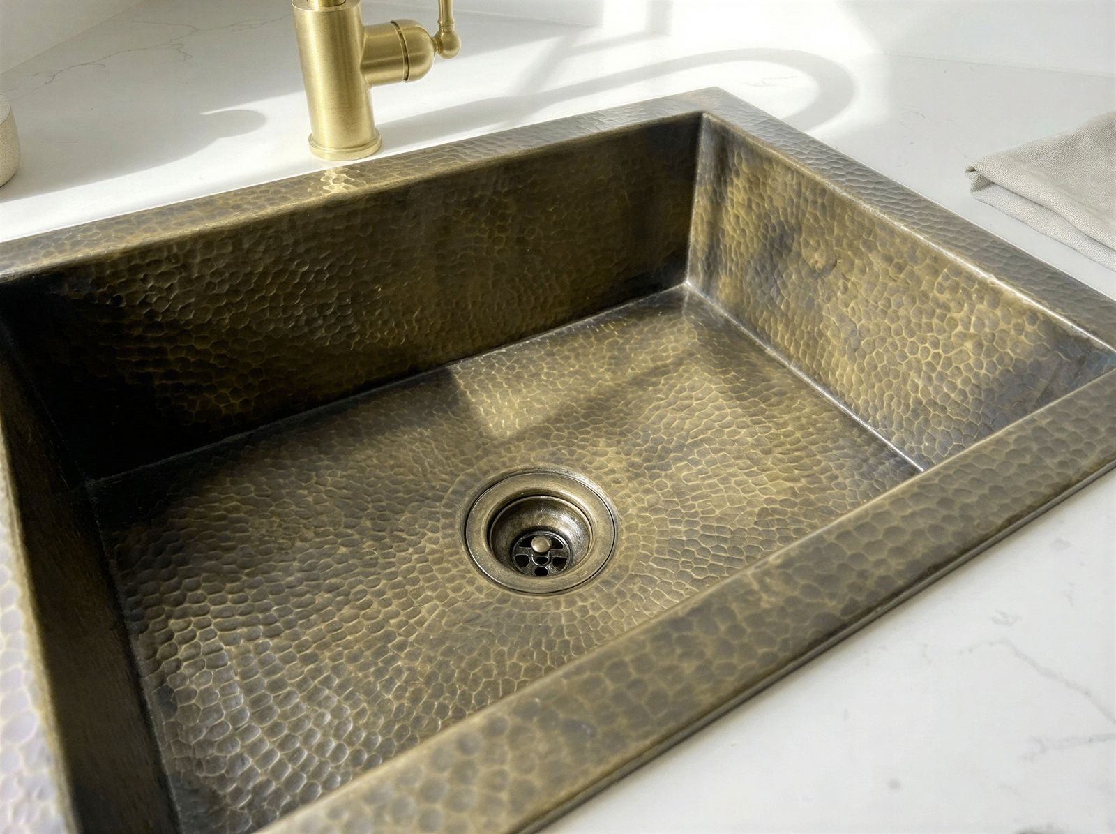 Bronze sink with a gold faucet on a white countertop