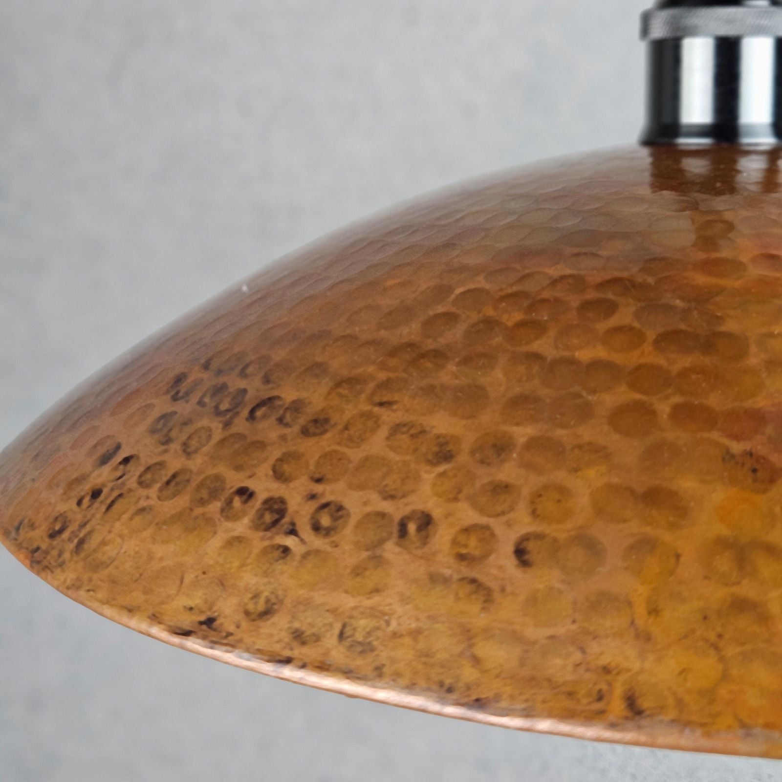 Close-up of a copper lampshade with a textured surface on a gray background