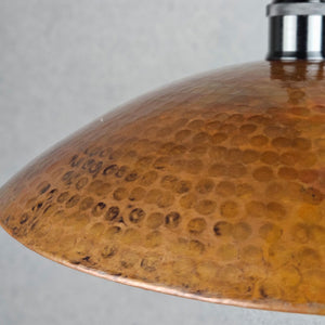 Close-up of a copper lampshade with a textured surface on a gray background