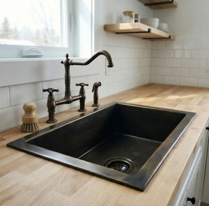Black kitchen sink with bronze faucet in a modern kitchen setting