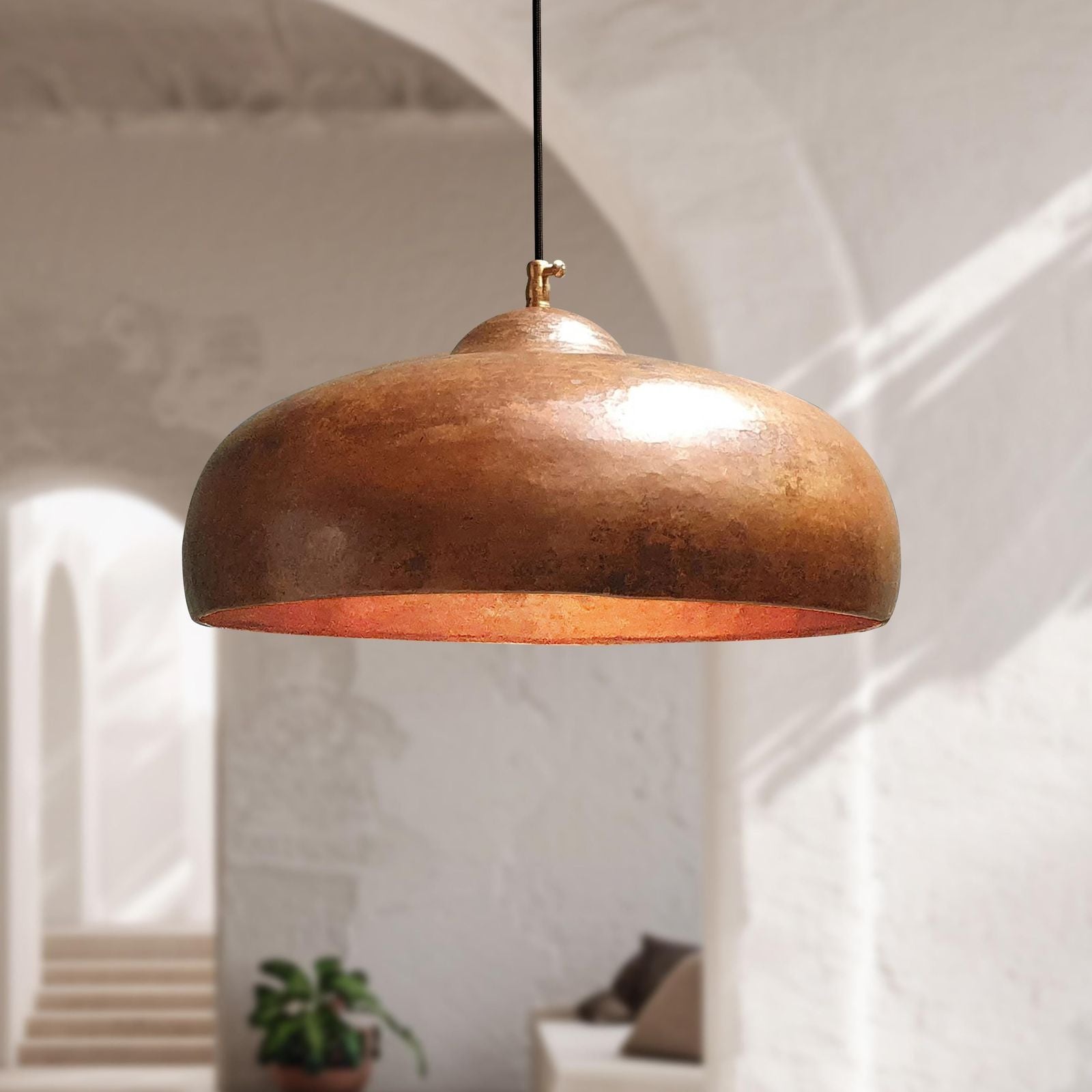 copper pendant light hanging in a room with white walls and minimal decor.