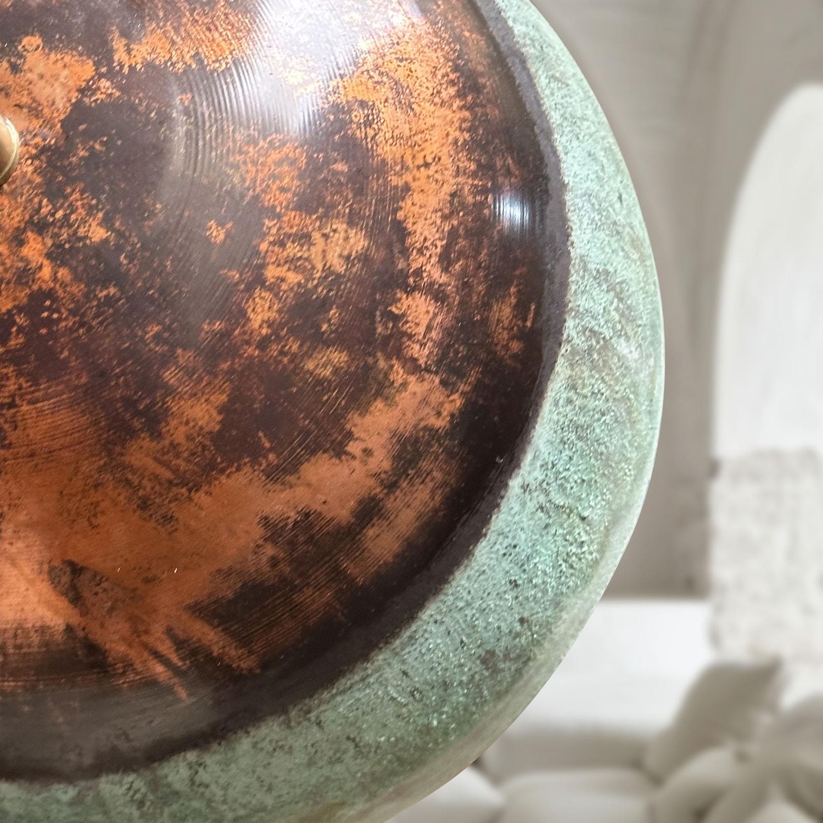 Close-up of a textured round object with copper and greenish-brown colors.