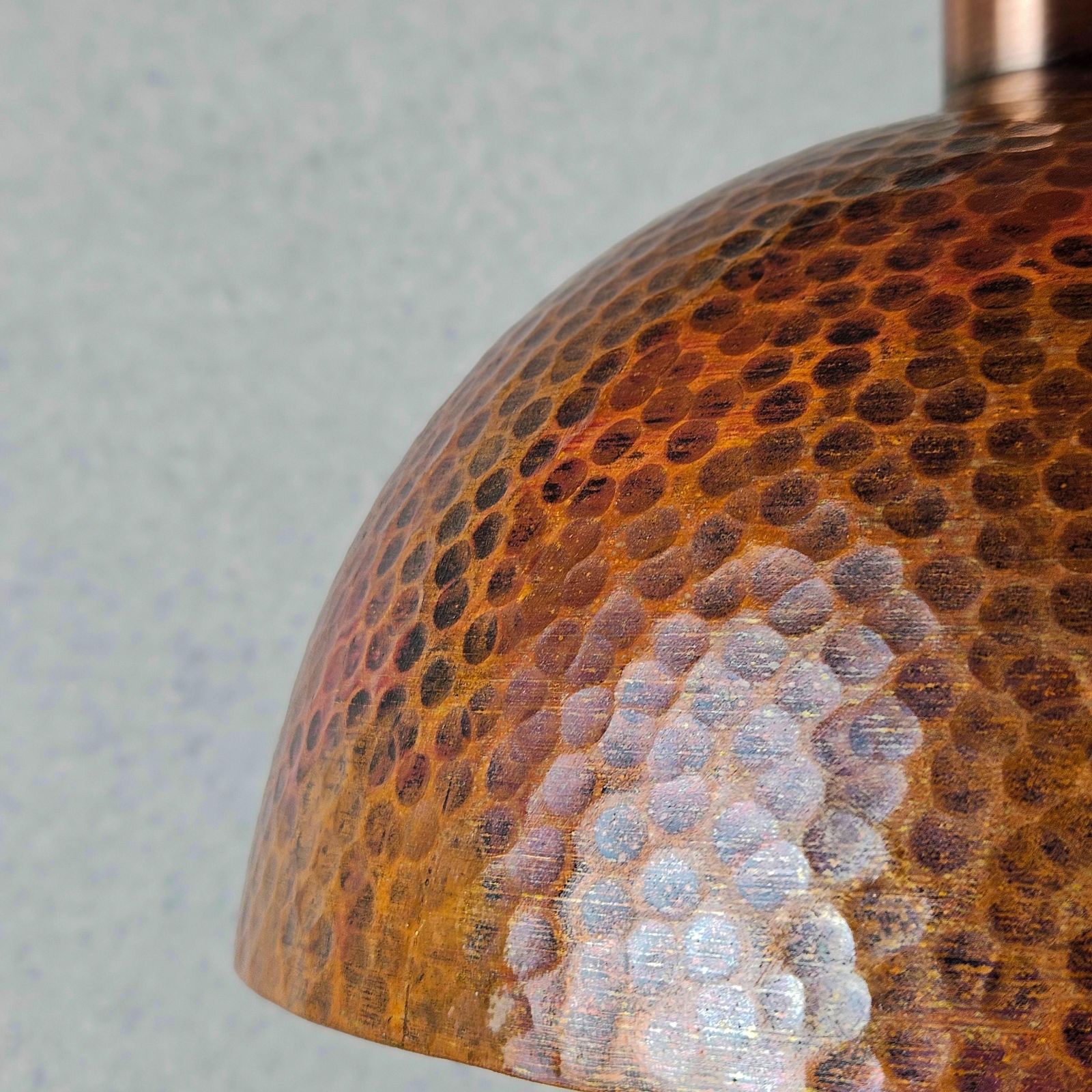 Close-up of a textured copper light fixture against a neutral background