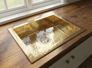 Gold sink on a wooden countertop with a window in the background