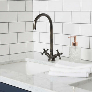 Bathroom sink with white marble countertop, dark blue cabinets, and white tiled wall.