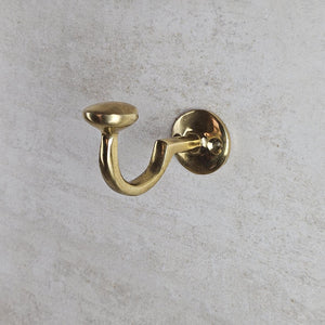 Gold wall hook on a gray concrete background
