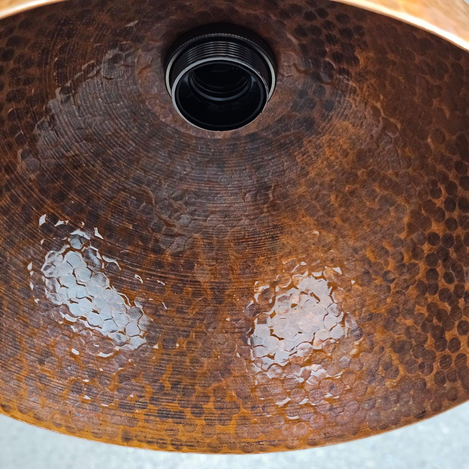 Close-up of a copper sink with textured surface and drain hole.