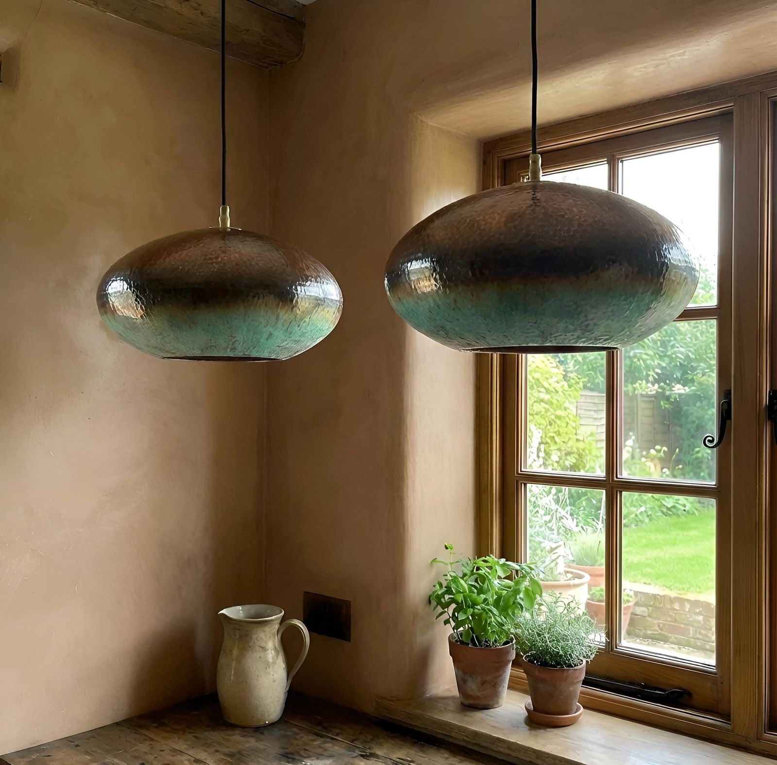 Two hanging pendant lights in a room with a window and plants on a windowsill.