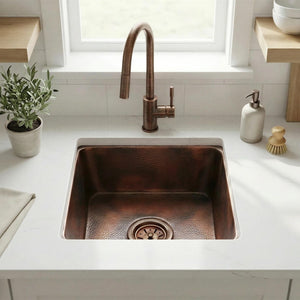 Copper kitchen sink with a bronze faucet in a modern kitchen setting.