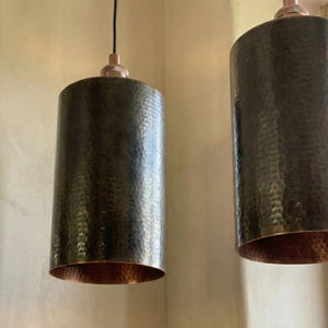 Two dark bronze pendant lights hanging against a beige wall.