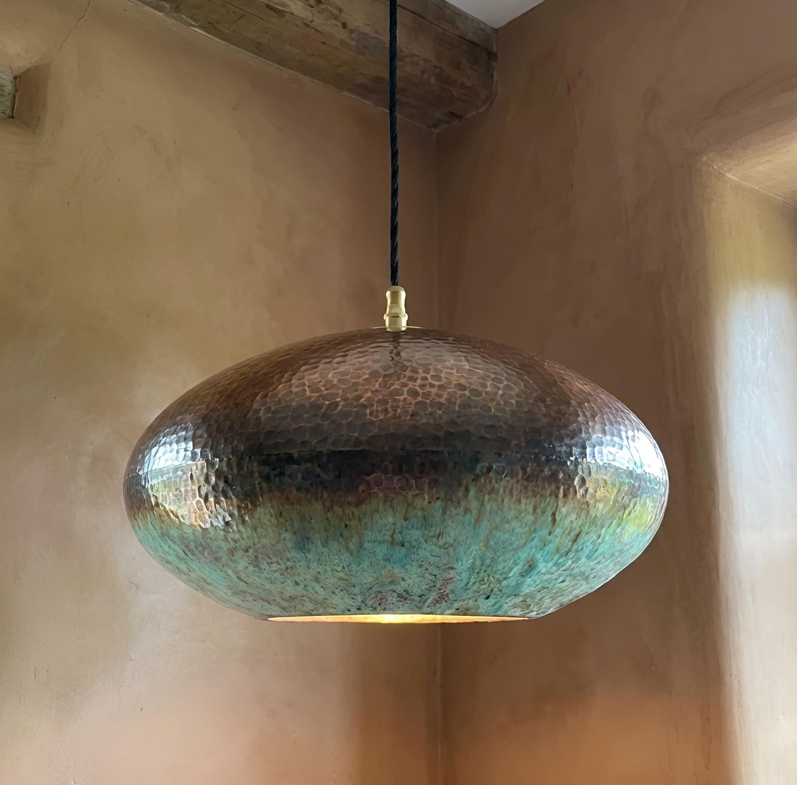 Copper pendant light hanging against a beige wall