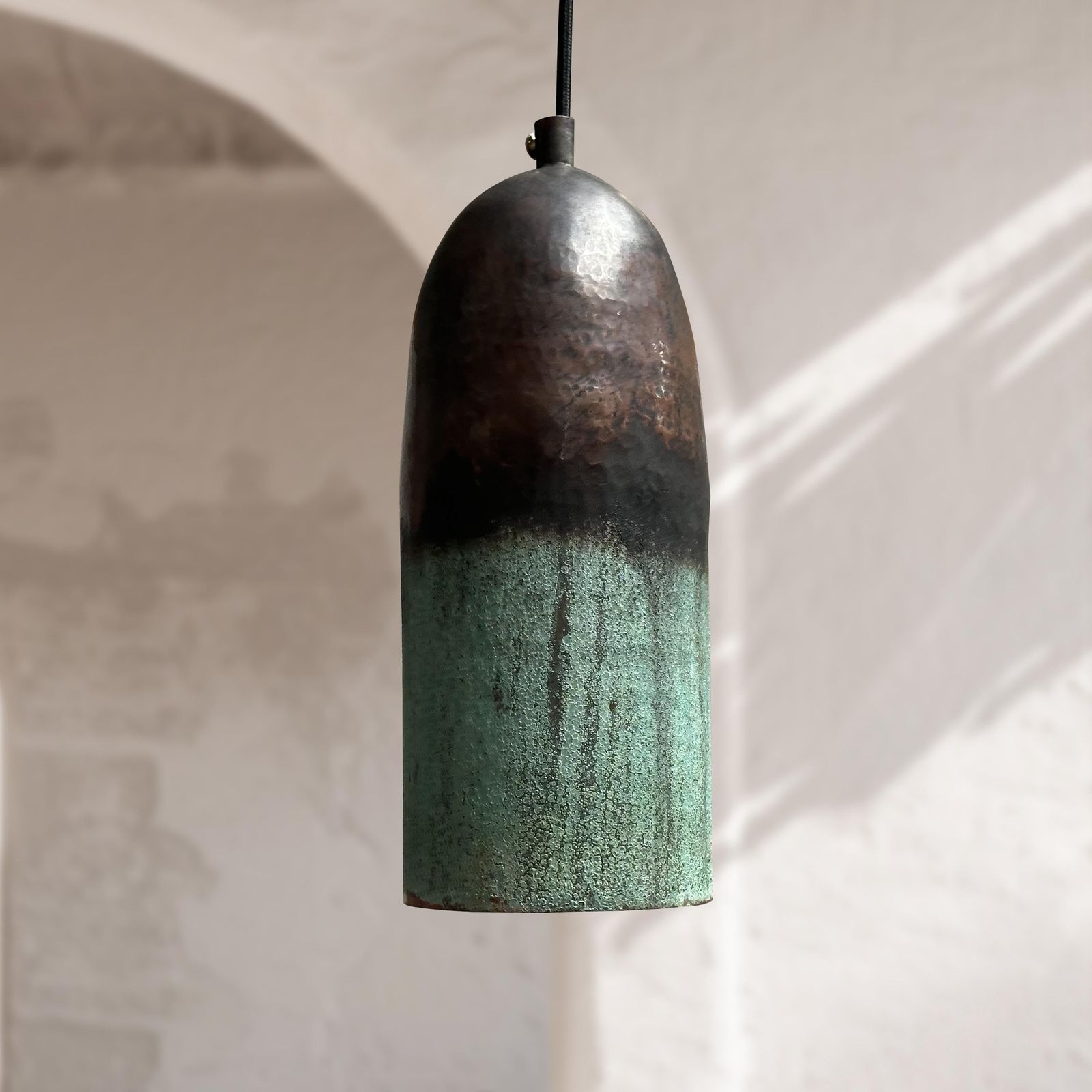 Pendant light with a textured design hanging against a neutral background