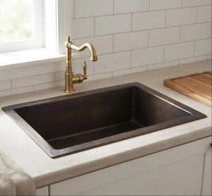 Black kitchen sink with a gold faucet in a modern kitchen setting.