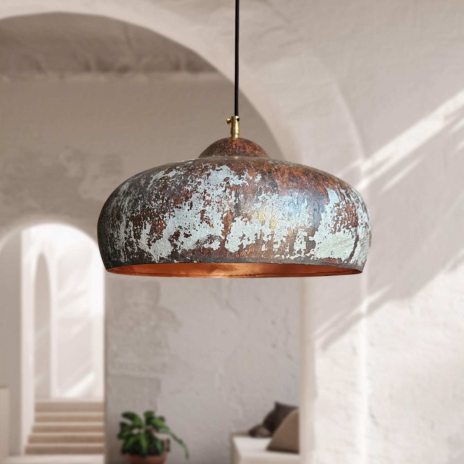 Rustic pendant light hanging in a room with architectural arches.