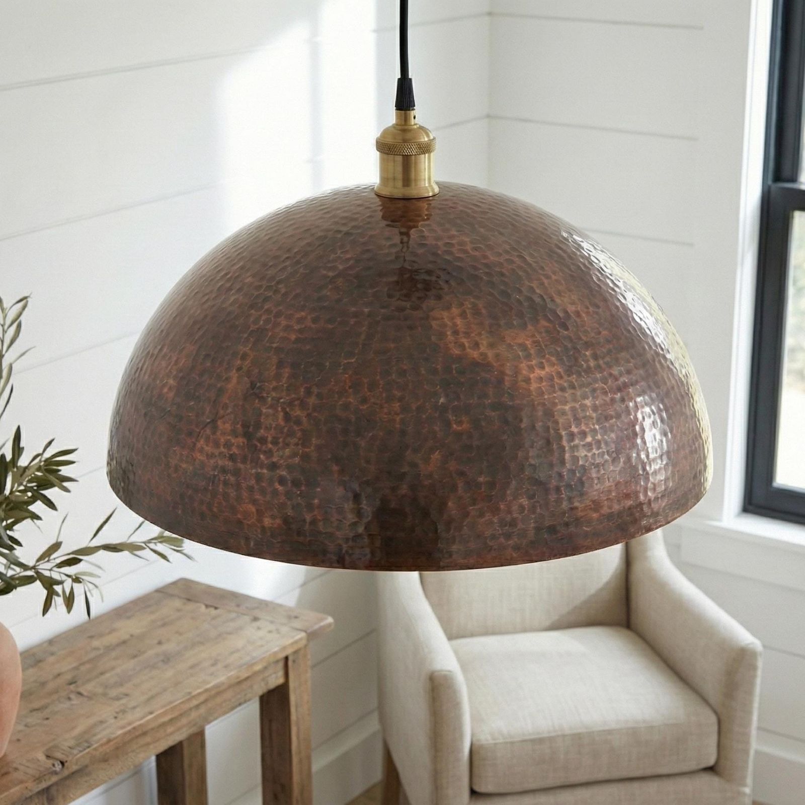 Hammered copper pendant light in a room with a chair and wooden table.