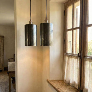 Two pendant lights hanging in a room with a window and wooden shelf.