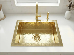 Gold sink with faucet on a white countertop