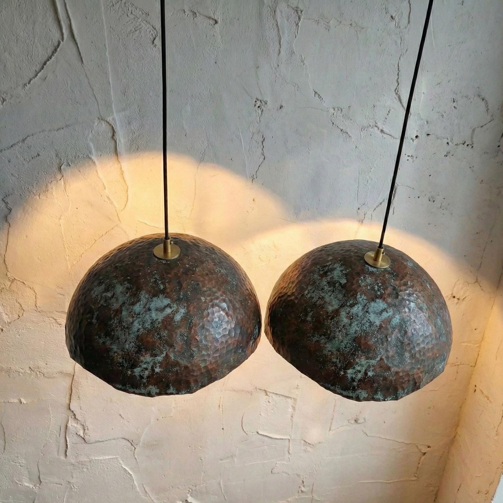 Two rustic pendant lights hanging against a textured wall.