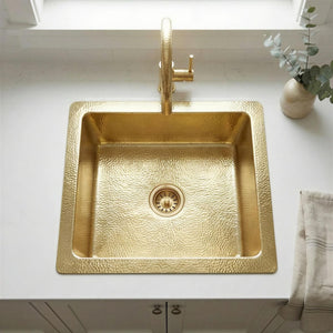 Gold kitchen sink with faucet on a white countertop