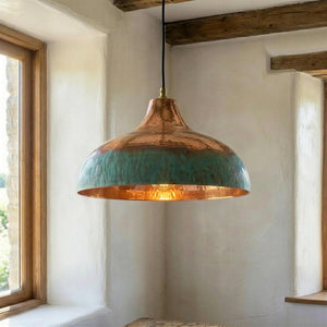 Copper and turquoise pendant light hanging in a room with wooden beams and large windows.