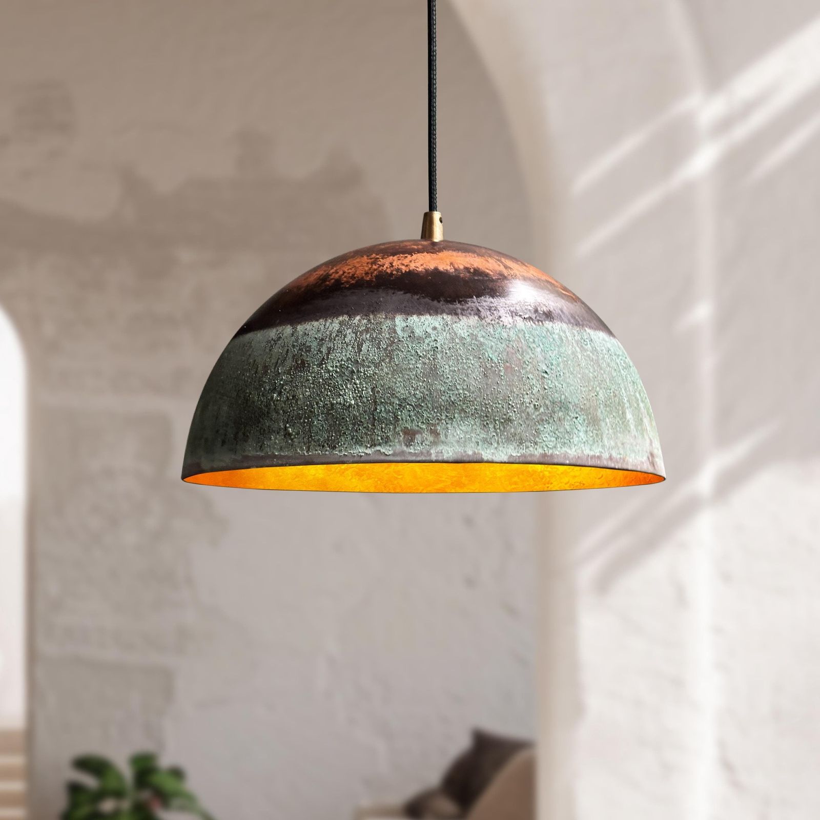 Pendant light with a textured green and brown design hanging against a neutral wall.