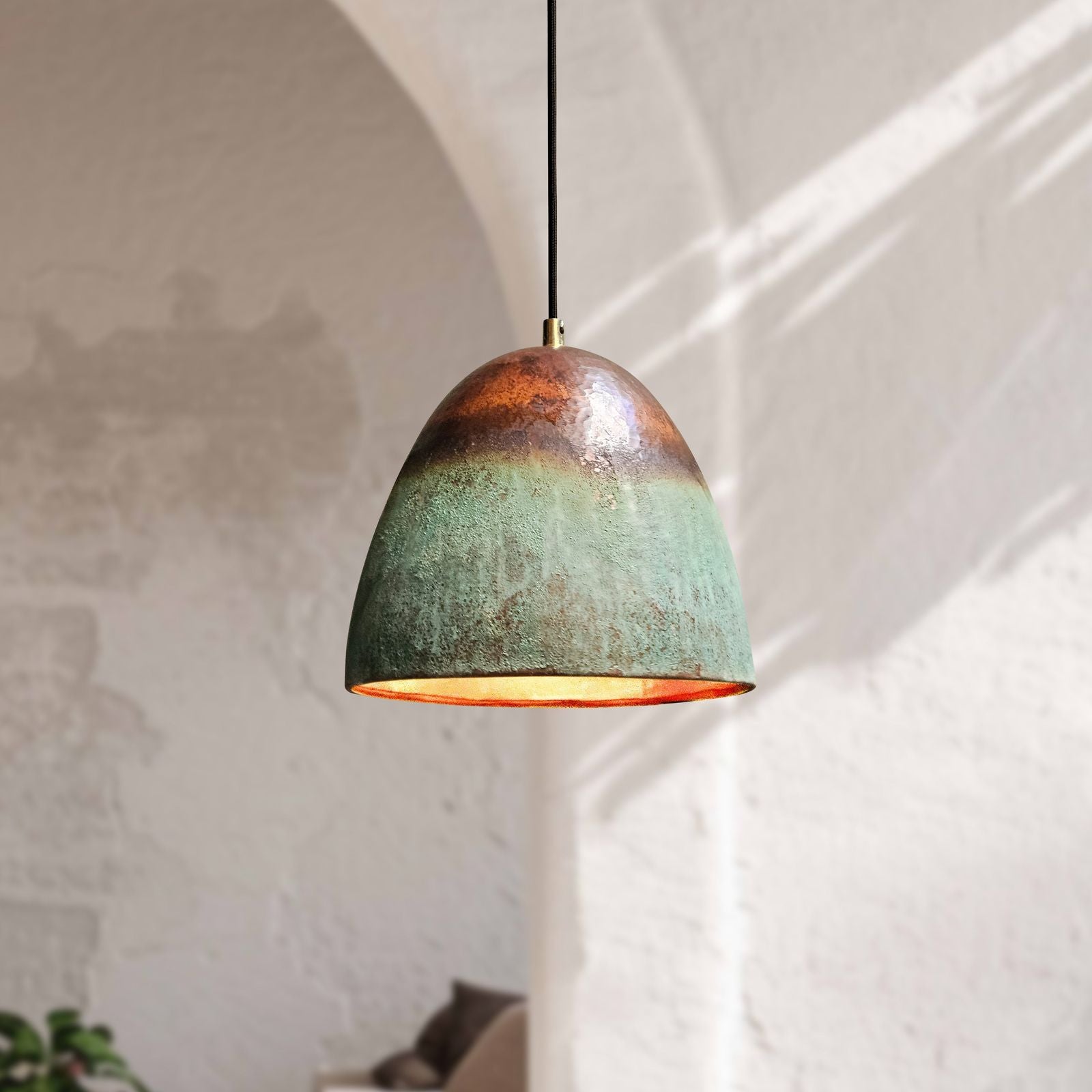Green pendant light hanging against a white wall with architectural details