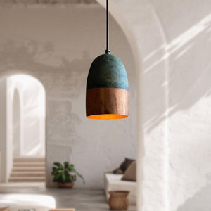 Pendant light with green top and copper bottom in a blurred room setting