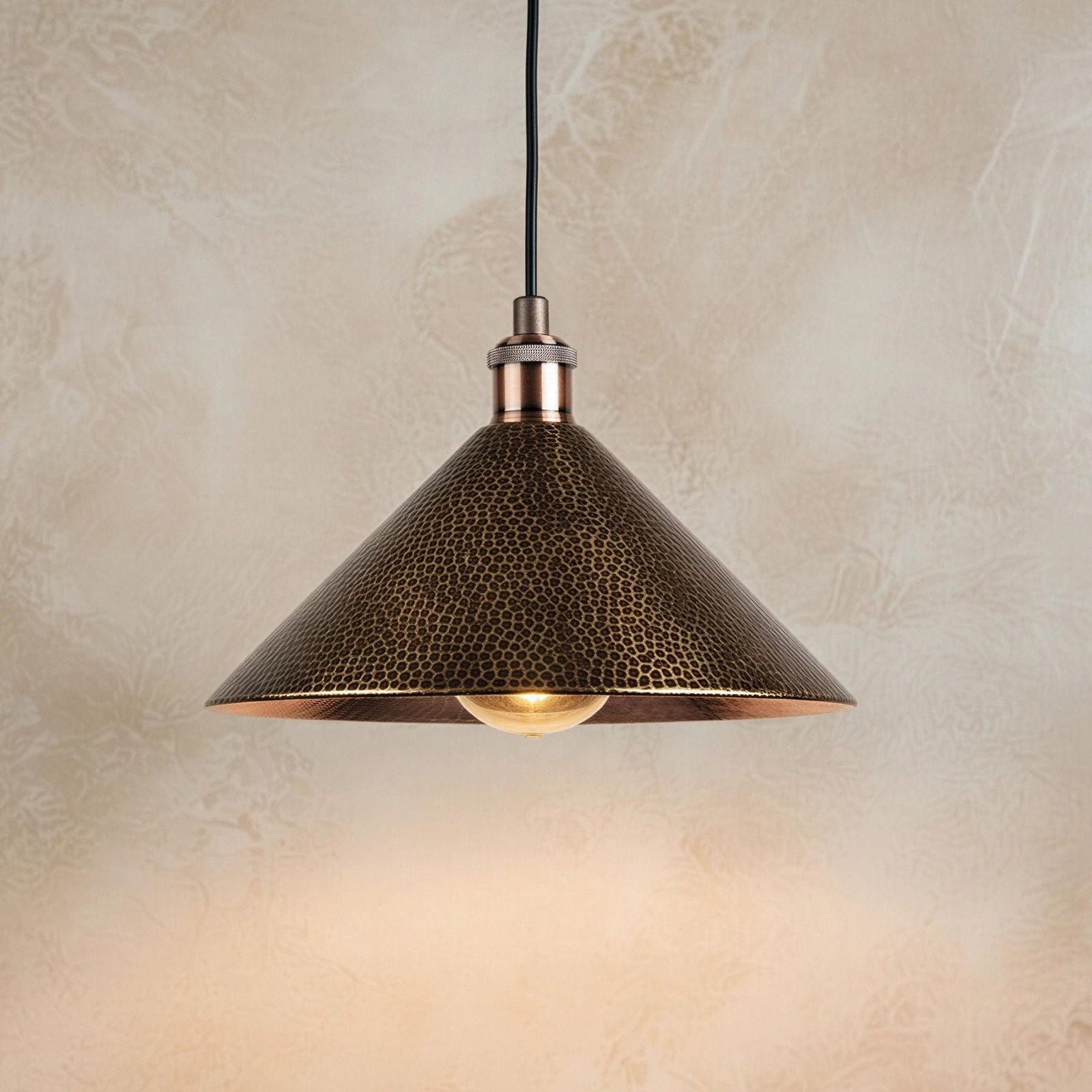 Bronze pendant light with textured shade on a beige wall