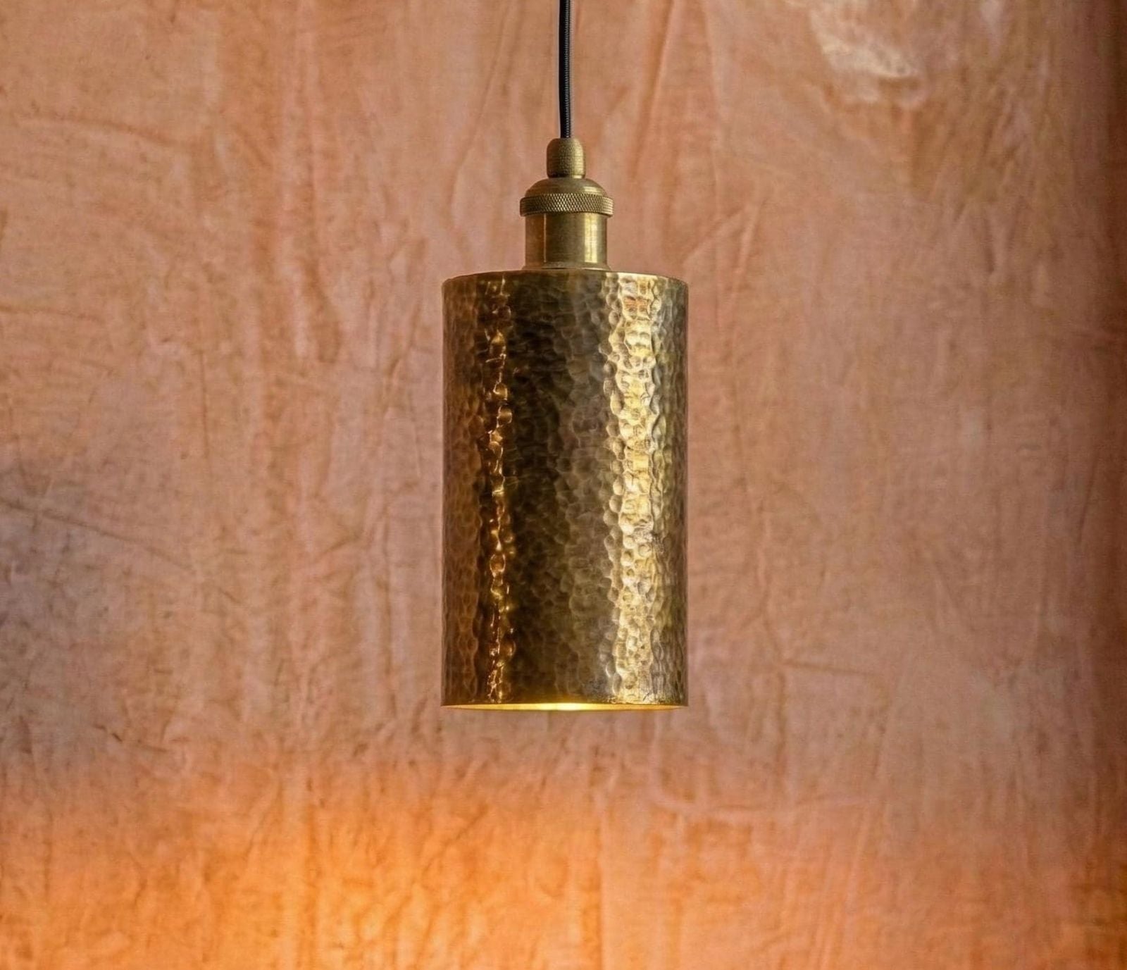 Gold pendant light against a textured brown wall