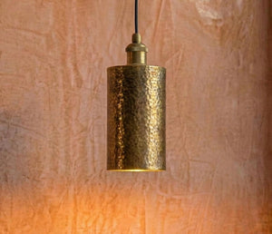 Gold pendant light against a textured brown wall