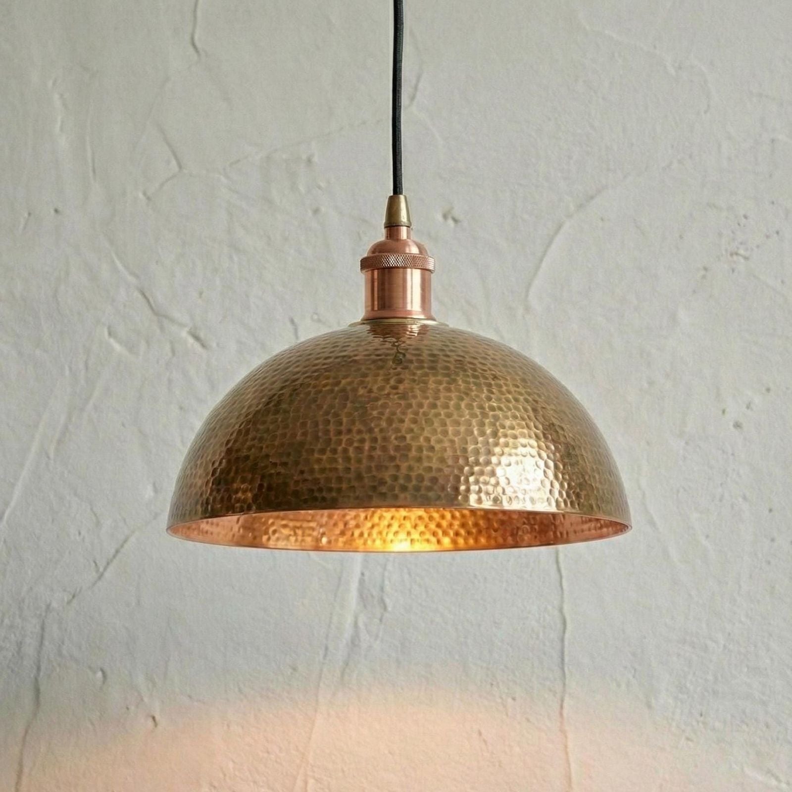 Hammered copper pendant light against a textured white wall