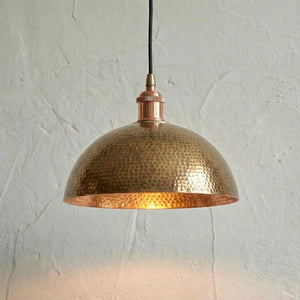 Hammered copper pendant light against a textured white wall