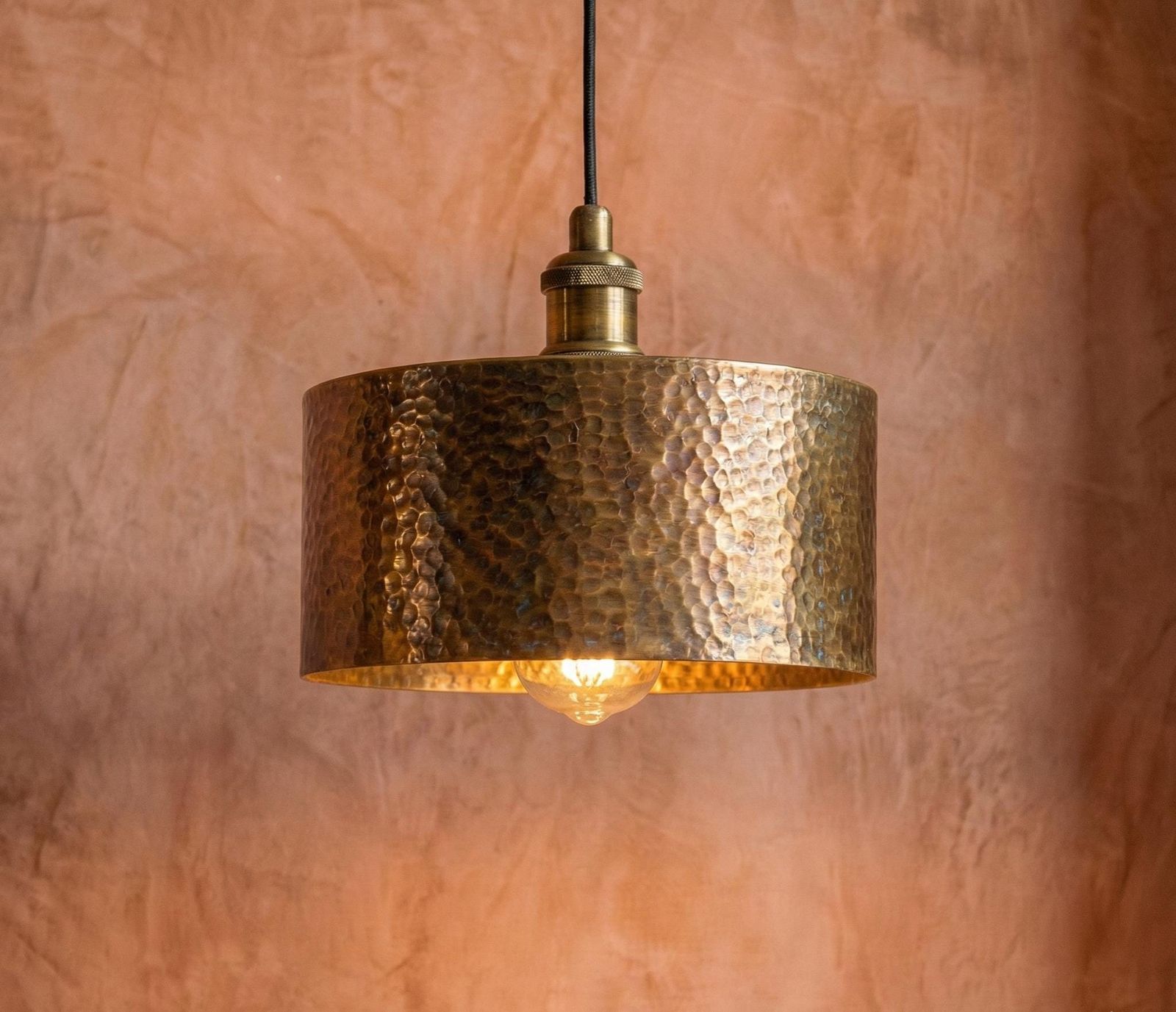 Hammered copper pendant light against a textured brown wall