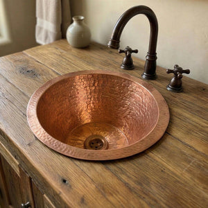 Copper sink on a wooden countertop with a faucet